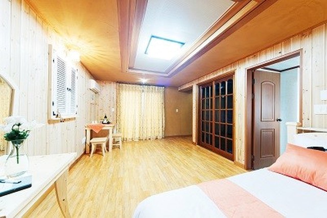 침대와 넓은 바닥 공간이 있는 목재 마감 객실